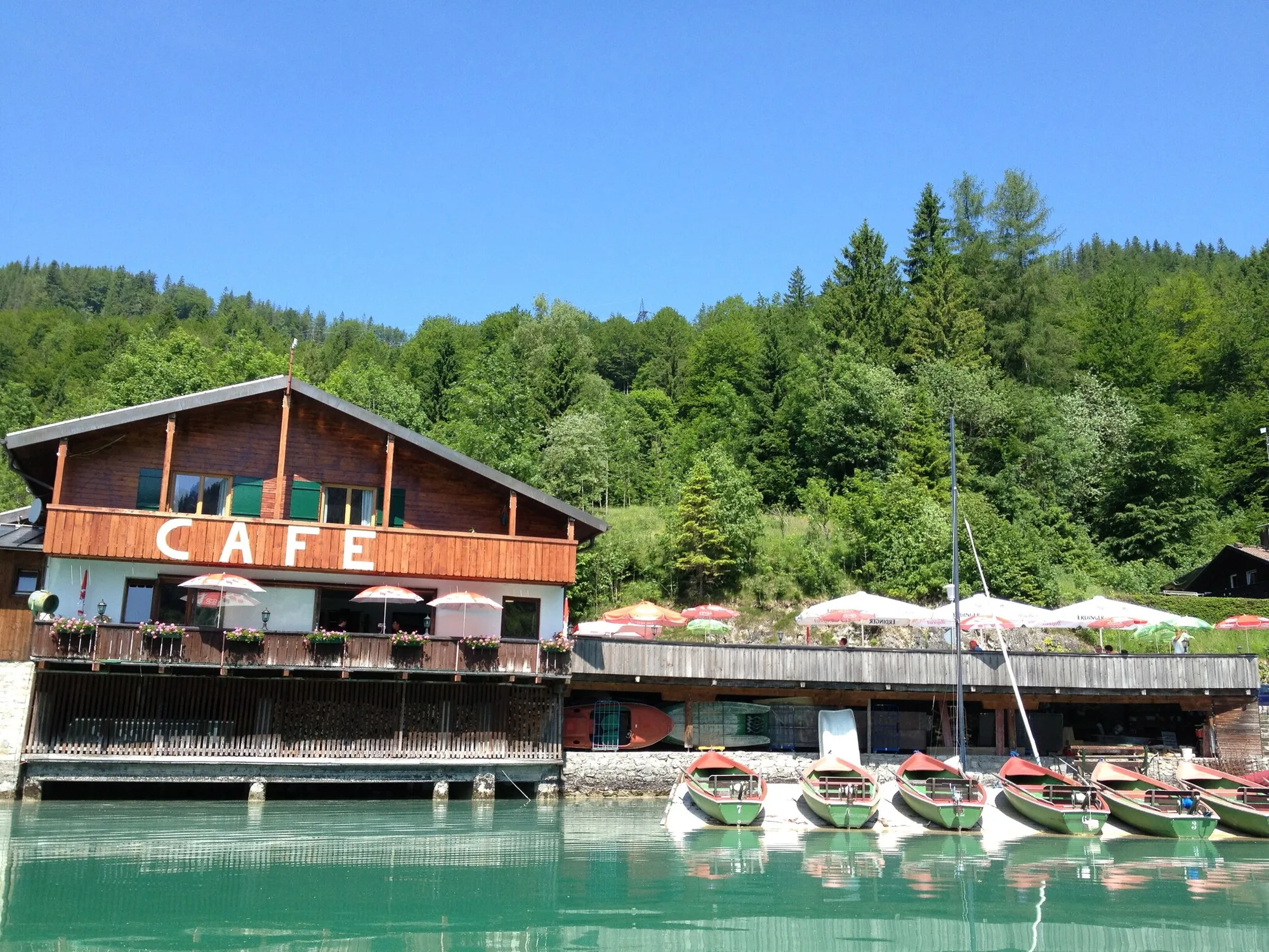 Echtes Foto: das Café der Familie über dem Wasser, davor die grünen Ruderboote am Steg